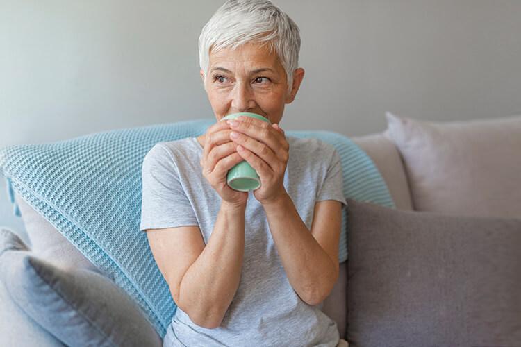 kvinne som sitter i sofa og holder en kopp