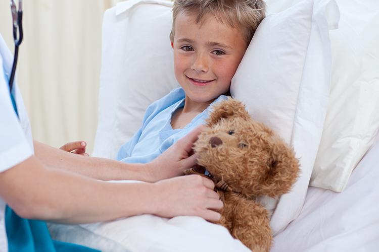 Young boy with teddy bear in bed