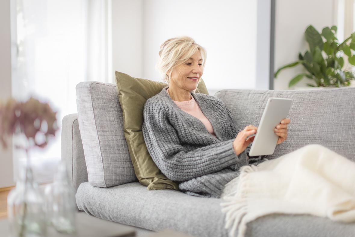 Patientin mit Tablet liegt auf dem Sofa - verlinkt zu Hochkalorische Trinknahrung (Der Einfluss der Ernährung)