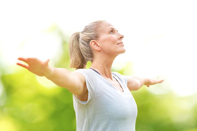 Woman smiling & stretching  her hands under the sun