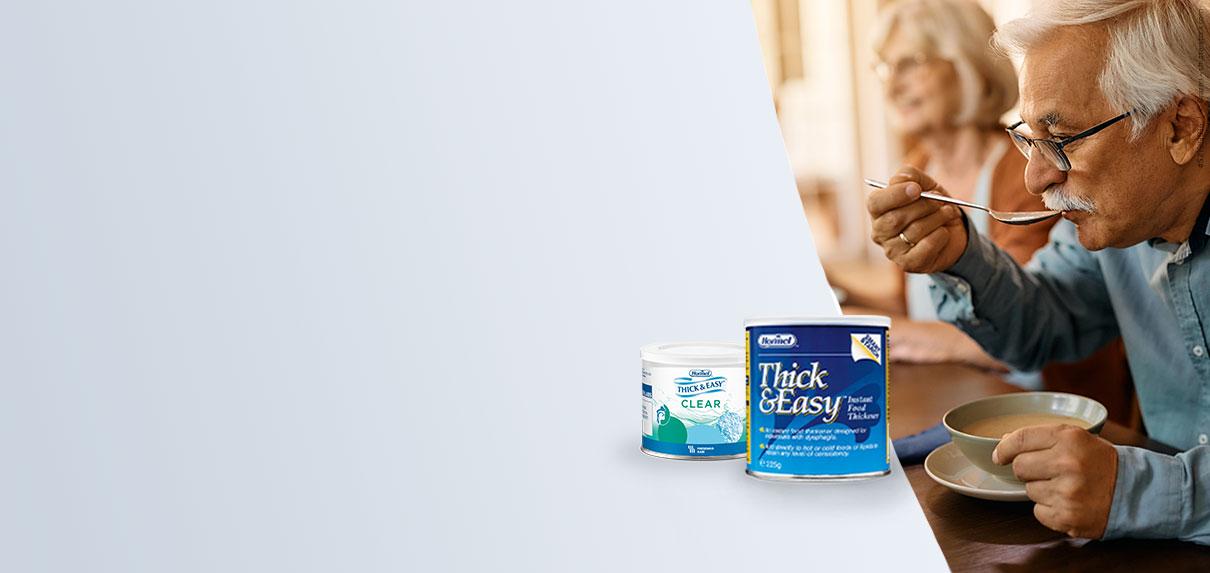 Opa löffelt eine Suppe, die mit den Andickungspulvern, Thick & Easy oder der CLEAR- Variante, im Vordergrund angedickt wurde. 