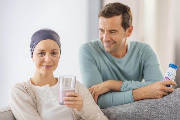Kalorienreiche Ernährung bei Krebs: Krebspatientin nimmt Fresubin Trinknahrung an der Seite ihres Mannes zu sich