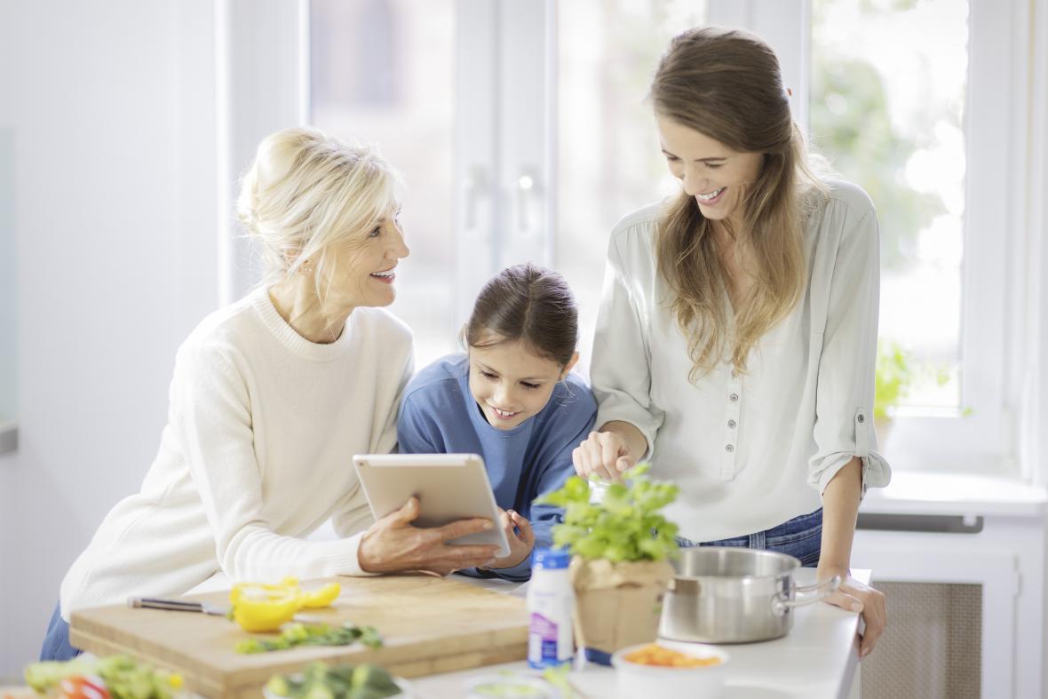 Ältere Patientin, Tochter und Enkelin schauen sich Rezepte auf Tablet an - verlinkt zu Rezepte