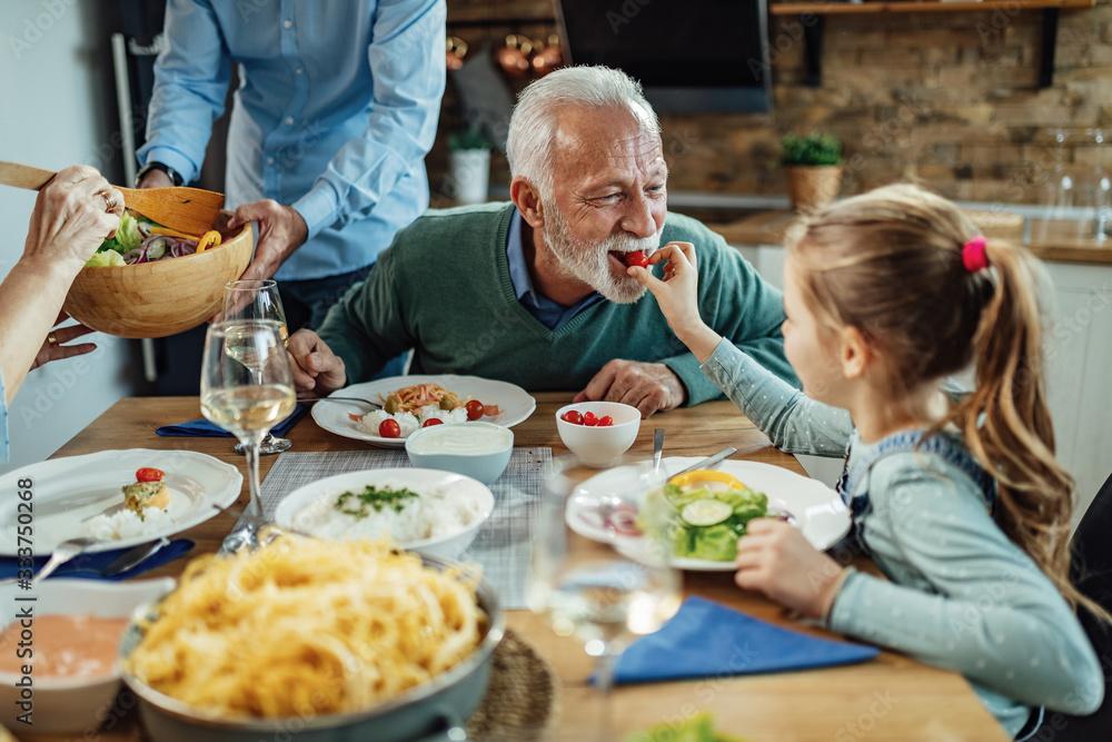 une petite fille donne un fraise à son grand pere.